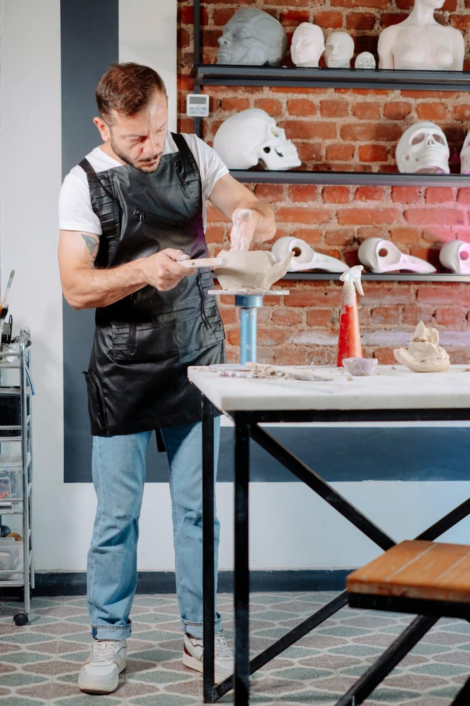 Mann formt Tonkunst in einem Atelier mit fertigen Stücken.